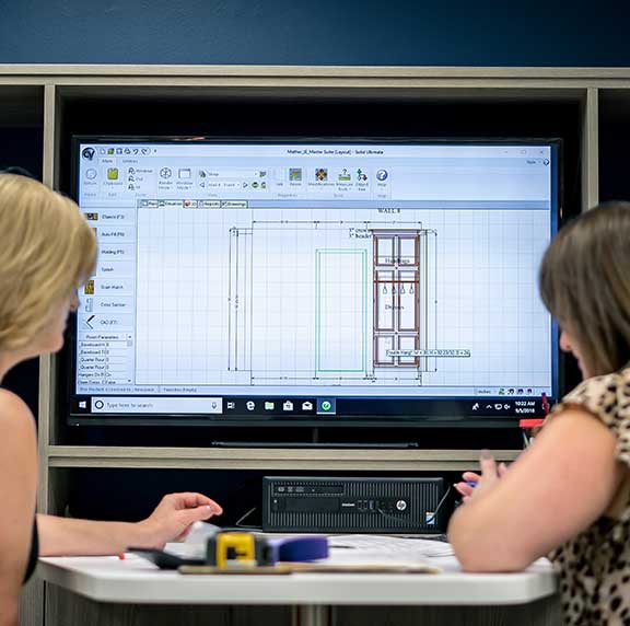Two designers drawing up blueprints of a design project