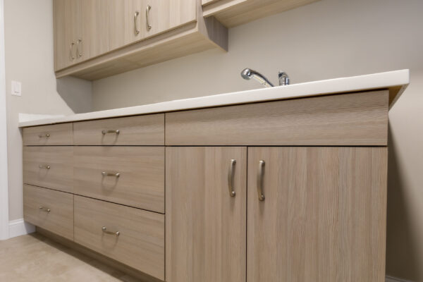Light wood cabinetry with silver handles, white countertop, and modern faucet.