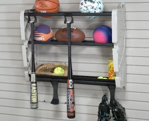 Wall-mounted sports equipment organizer with basketball, soccer ball, football, softballs, bats, mitt, and skates.