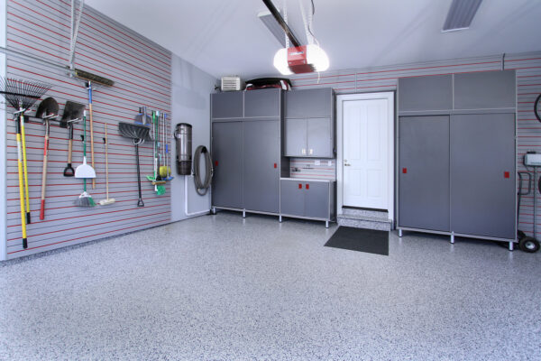 Organized garage with gray slatwall, matching cabinets, smooth epoxy floor, and various tools neatly stored.