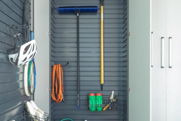 Garage storage cabinet with open doors, gray slatwall, garden tools, and a rooftop cargo box on top.