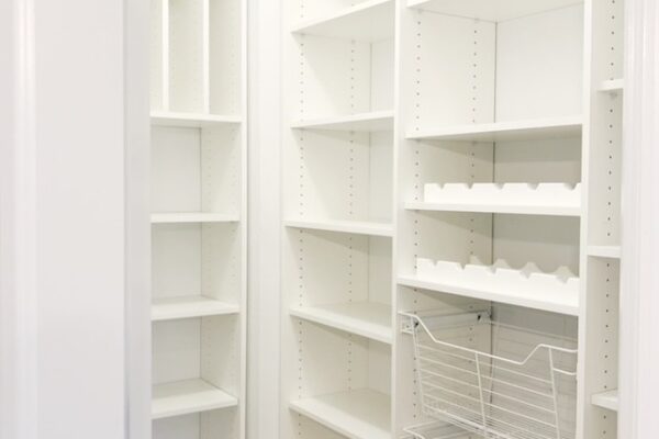 White pantry with adjustable shelves, wire pull-out baskets, and wine racks.