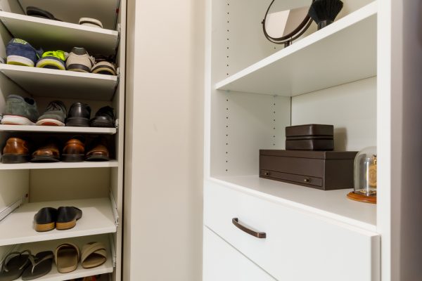 Custom closet with shoe racks on the left and white shelves with brown leather boxes, a mirror, and a brush on the right.