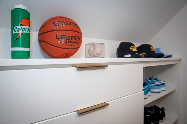 Green Gatorade bottle, basketball, cased baseball, and baseball caps on white shelves.
