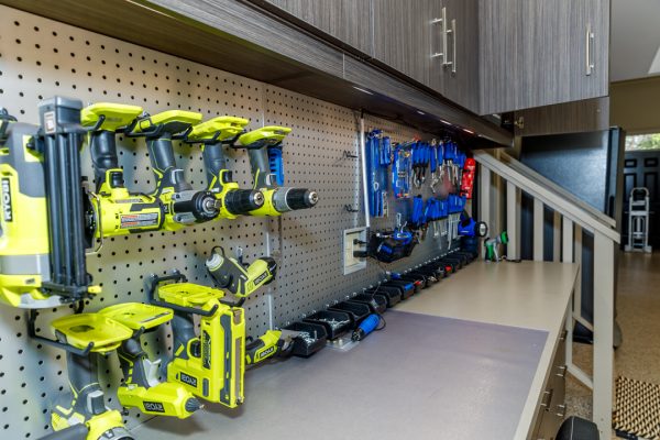 Garage workstation with pegboard organizing cordless drills, tools, and hardware bins above a workbench.