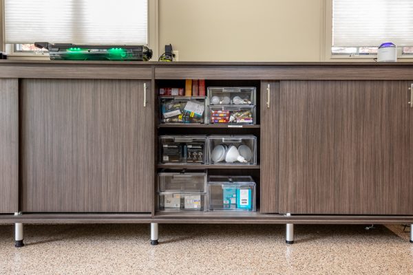 Brown wood-grain cabinet with sliding doors, a display section with clear bins of lightbulbs, and small items.