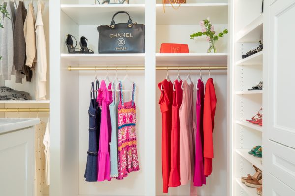White walk-in closet with colorful dresses, designer handbags, and high heels.